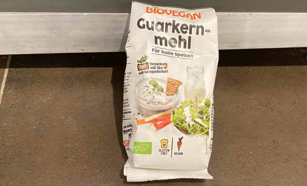 Veganes und glutenfreies Guarkernmehl im Test befindet sich in seinem weißen Beutel auf einem braunen Boden.