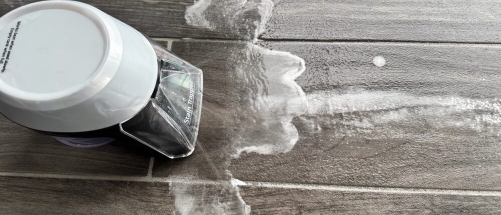 Der Bissell 15585 SpotClean Pet Pro Portable sprüht Wasser auf einen Fliesenboden zur Reinigung eines Stärkeflecks.