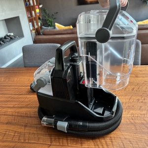 Eine Hand setzt einen Behälter in den Bissell SpotClean 3689N ein