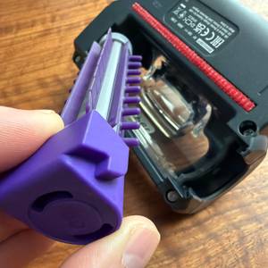 Eine Hand entfernt die Rolle am Aufsatz vom Black+Decker BHHV520BFP