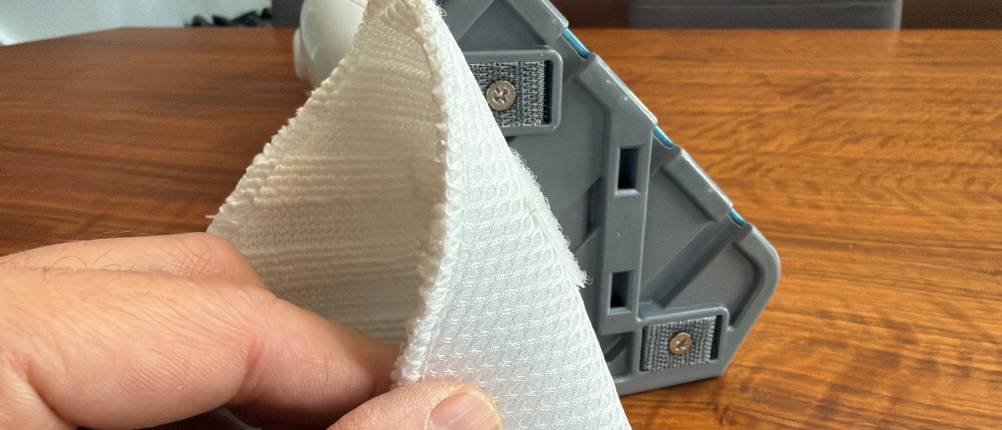 Eine Hand entfernt den Stoff vom kleinen Aufsatz des Black+Decker FSM1616-QS