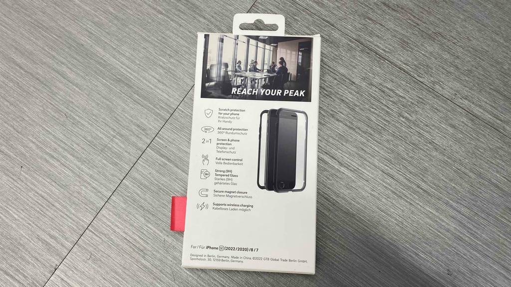 iPhone-SE-Panzerglas im Test: eine Verpackung mit Fokus auf die rückseitige Beschreibung liegt auf einer grauen Fläche.