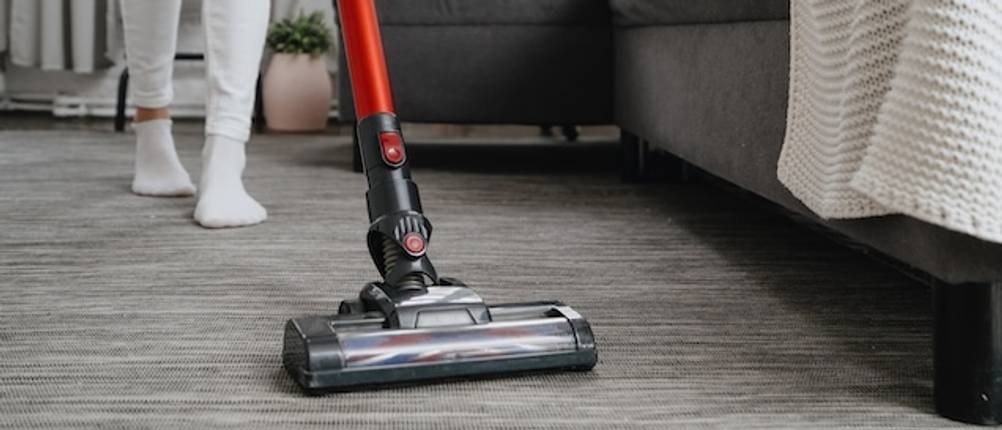 Black-und-Decker-Akku-Staubsauger mit einem roten Stiel auf einem grauen Parkettboden getestet.