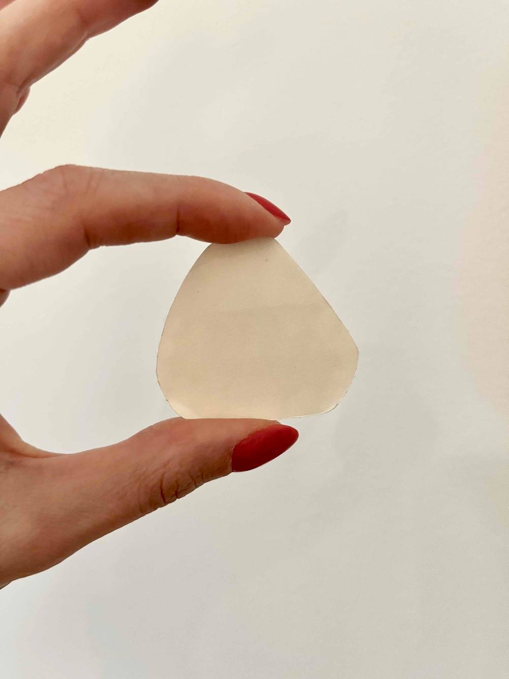 Eine Hand hält ein getestetes Blasenpflaster vor eine helle Wand.