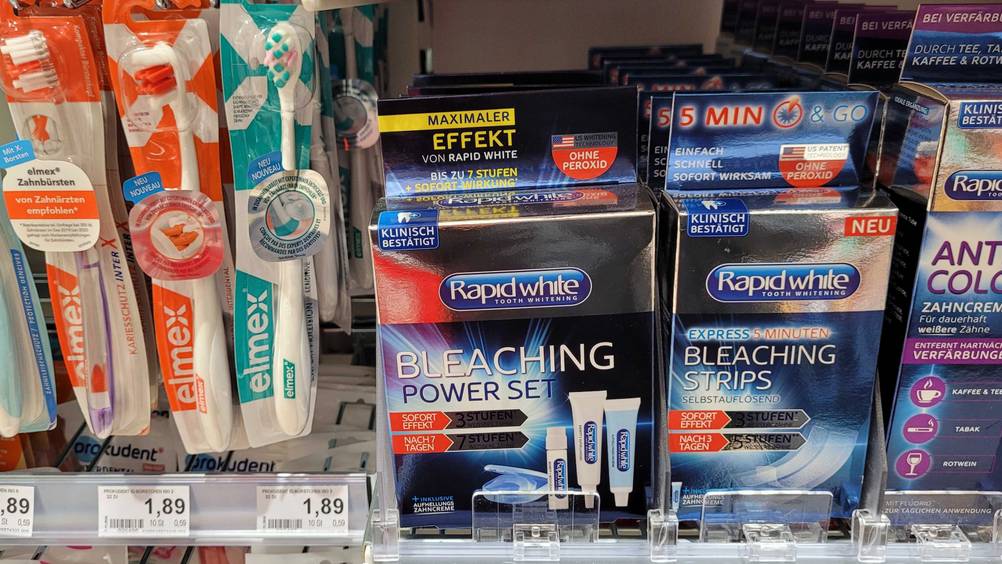Mehrere Packungen des getesteten Bleaching-Gels in einem Verkaufsregal neben anderen Produkten.