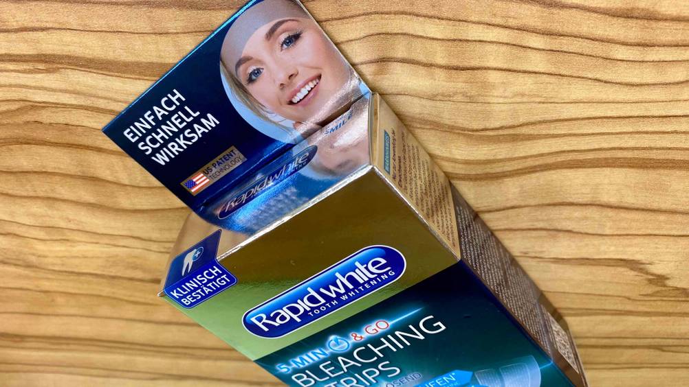 Nahaufnahme der Oberseite der Verpackung der Bleaching-Strips im Test auf einer Holzfläche.