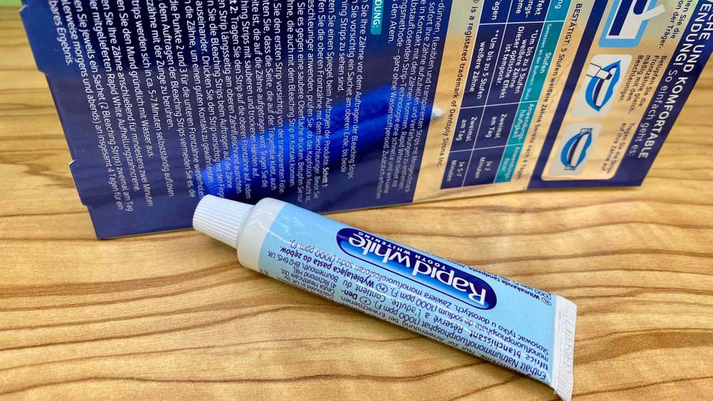 Eine Tube der getesteten Bleaching-Strips vor der Verpackung auf einem Holztisch.