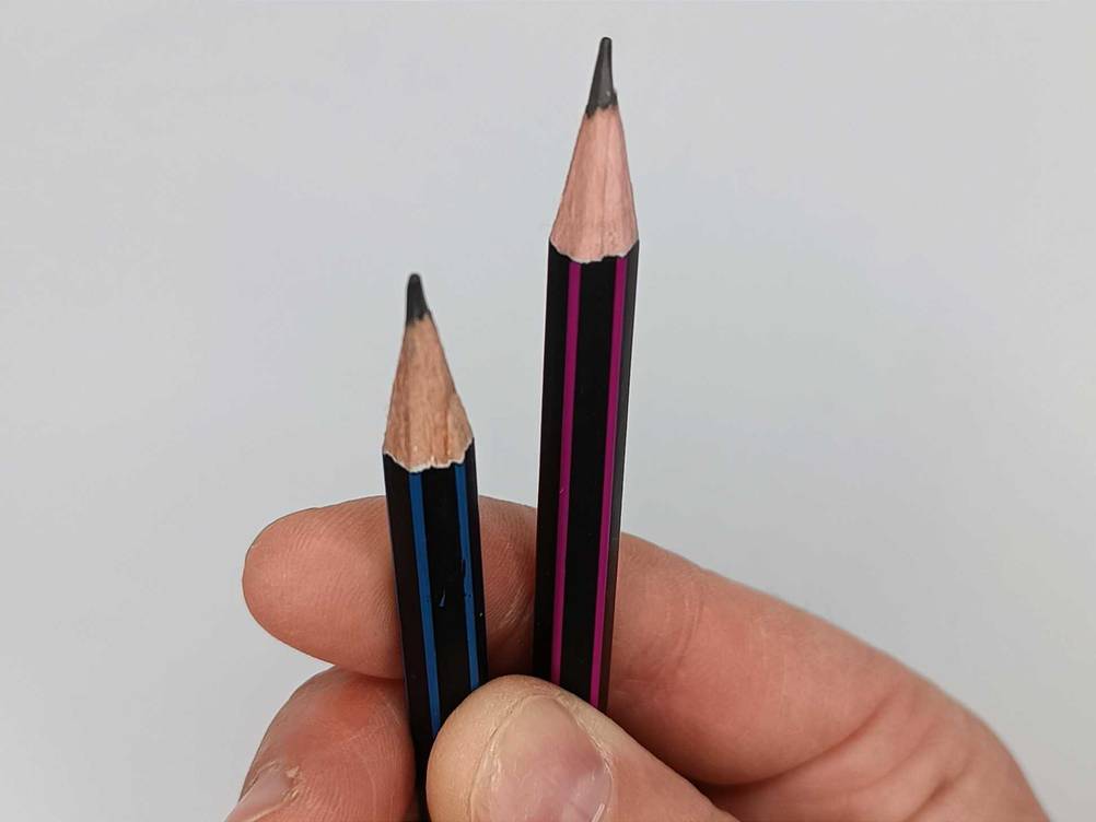 Bleistift im Test: Zwei Stiftspitzen zwischen den Fingern einer Hand vor einer hellen Fläche.