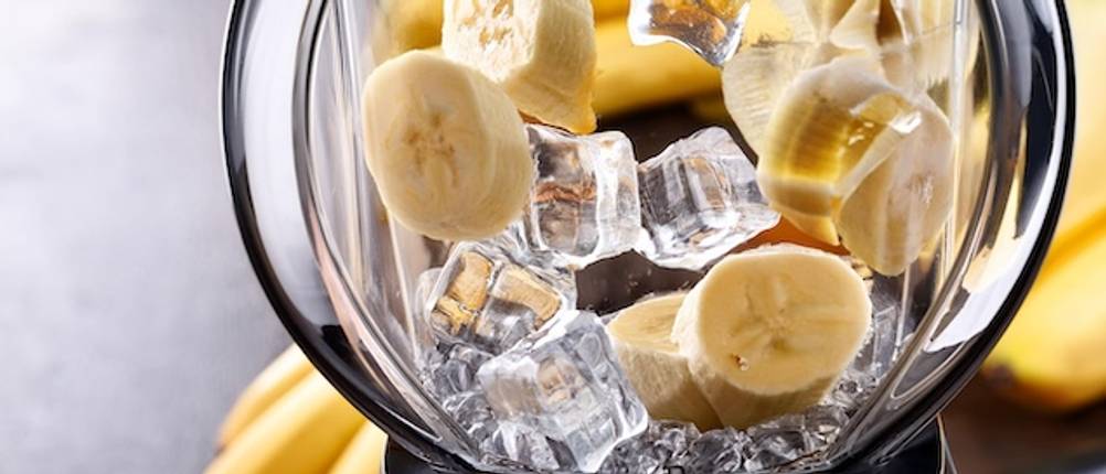 Die Mixer-Leistung im Test: Ein Mixerbehälter aus Glas ist gefüllt mit Eiswürfeln und Bananenscheiben.