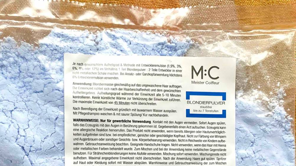Nahaufnahme der Informationen auf der Packung des getesteten Blondierpulvers mit Warnhinweisen.