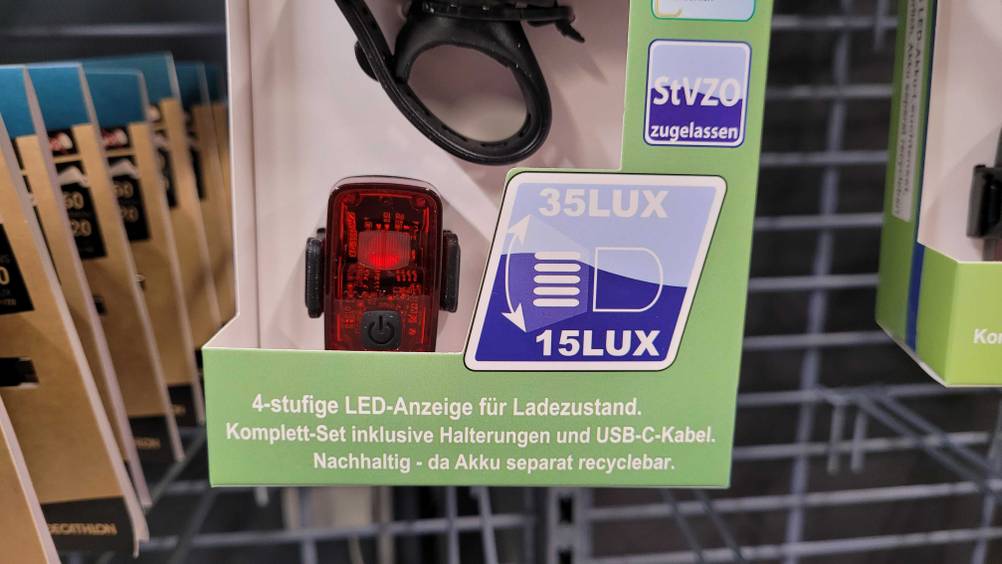 Im Test. Fahrradlampen-Set-Verpackung in hellgrünem Design, mit Fokus auf die Produktinformationen: inklusive 4-stufiger LED-Anzeige sowie Halterungen und USB-C-Kabel.