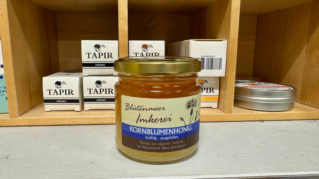 Getesteter Kornblumenhonig im Glas steht vor einem Verkaufsregal mit Schuhpflegeprodukten.