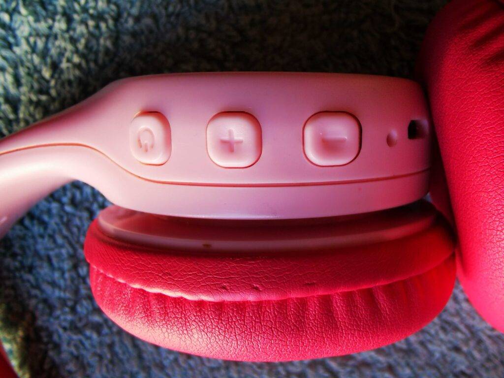 Nahaufnahme der Bedientasten an der Ohrmuschel des pinkfarbenen Bluetooth-Kopfhörers bis 50 Euro im Test.