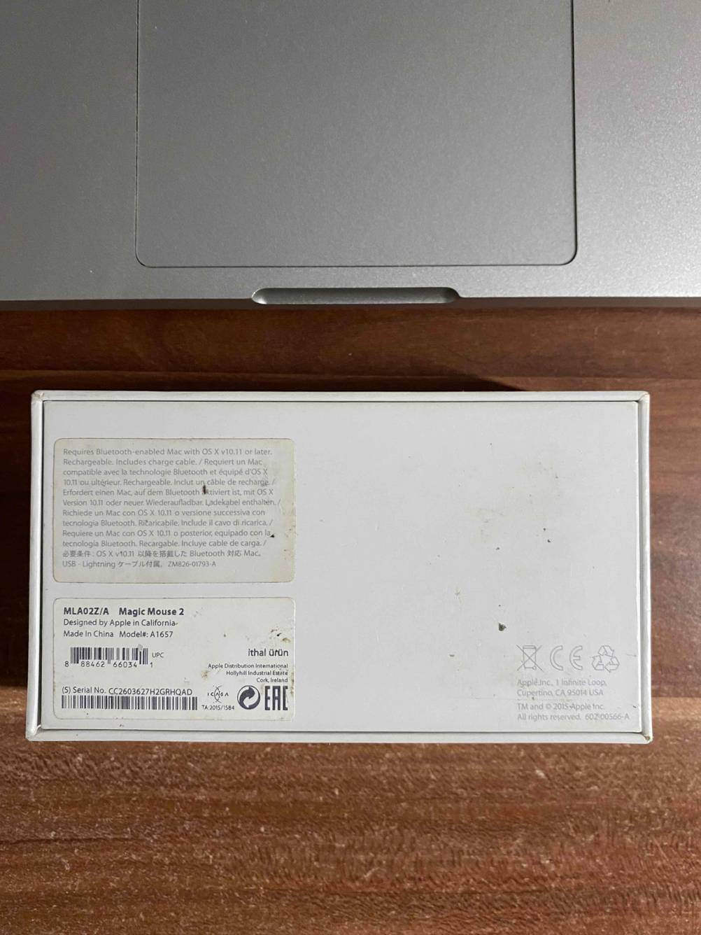 Rückseite der Originalverpackung der getesteten Bluetooth-Maus neben einem Laptop