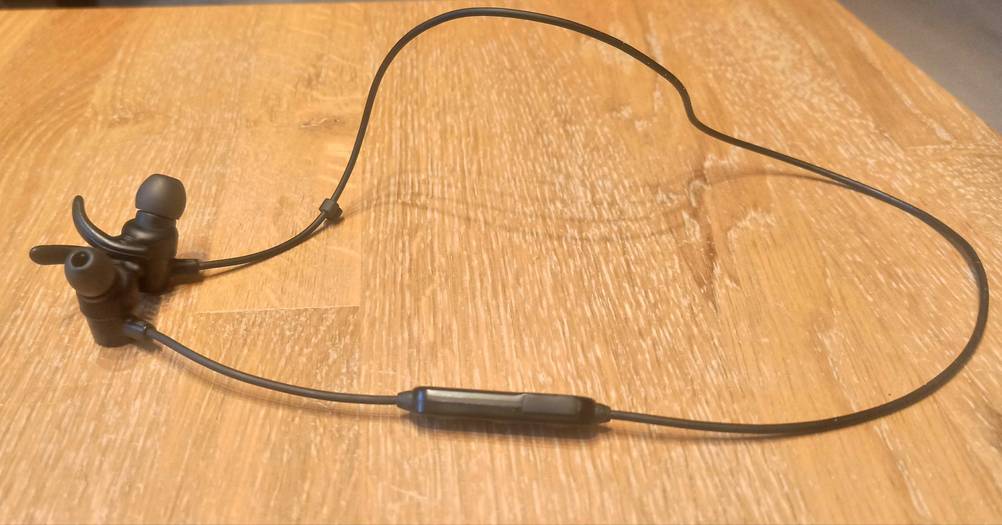 Ein getesteter Bluetooth-Sportkopfhörer auf einem Holztisch.