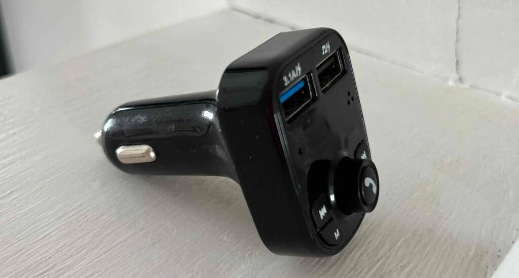 Ein getestetes Bluetooth-Autoradio in Schwarz für den Zigarettenanzünder von der Seite betrachtet, vor weißem Hintergrund.