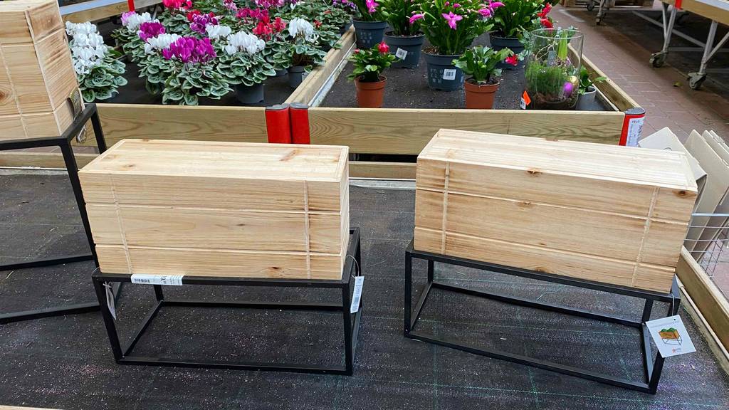 Zwei getestete Blumenkästen aus Holz befinden sich vor einem Blumenbeet. 