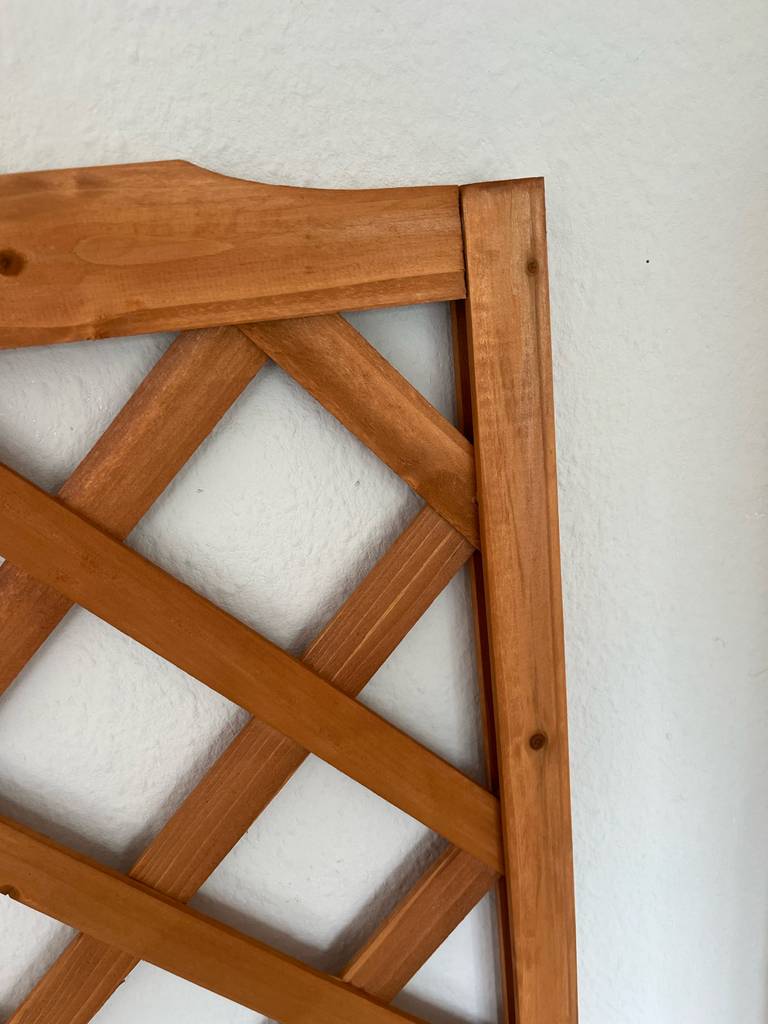 Detailansicht eines aus Holz gefertigten Blumenkastens mit Rankgitter im Test vor weißer Wand.