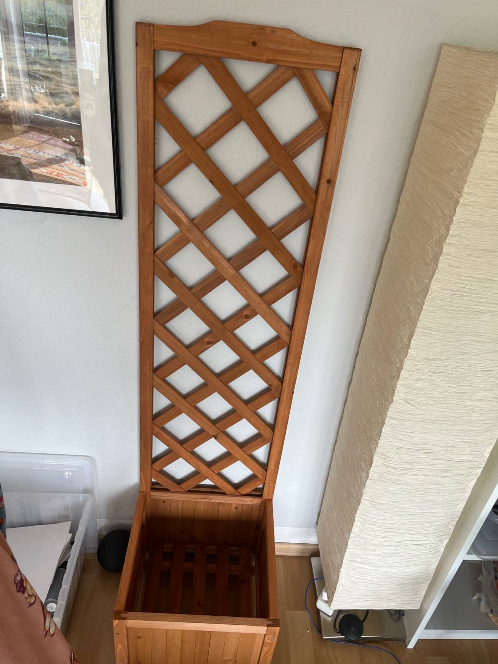 Ein getesteter Blumenkasten mit Rankgitter leer in einem Wohnzimmer stehend.