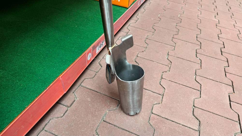 Nahaufnahme des Behälters des Blumenzwiebelpflanzers im Test von der Seite auf einem Steinboden.