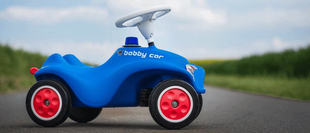 Bobby-Car im Test: Ein blaues Bobby-Car mit Sirene auf Asphalt.