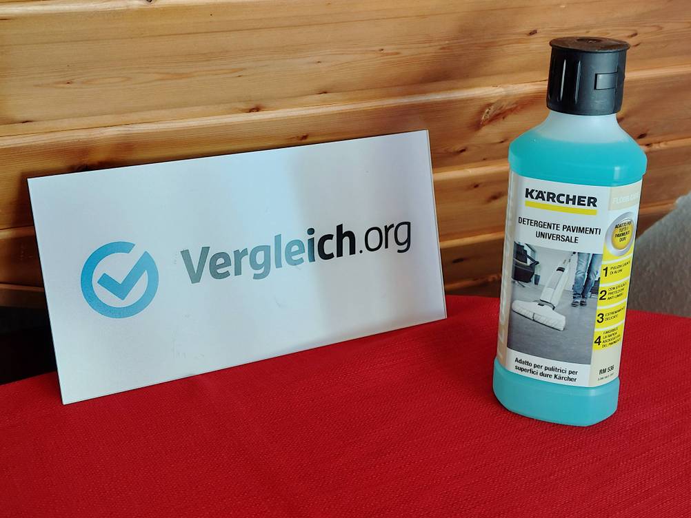 Eine Flasche mit Bodenreiniger steht neben einem Schild mit dem Schriftzug Vergleich.org