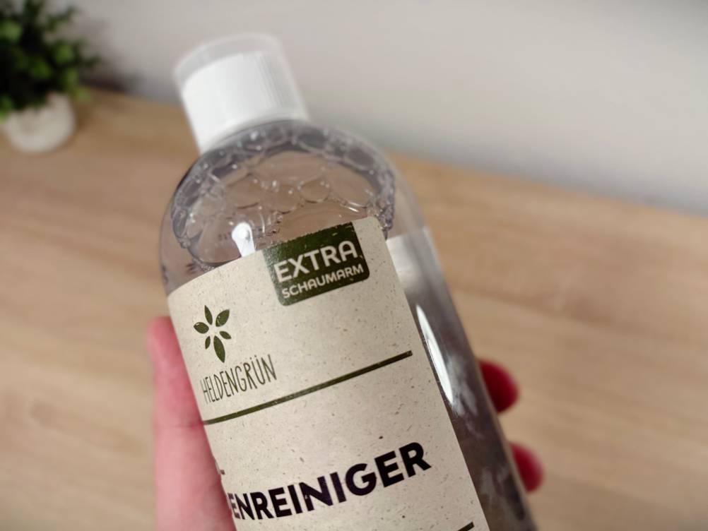 Eine Hand hält den Bodenreiniger von Heldengrün.