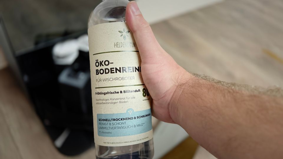 Eine Hand hält den Bodenreiniger von Heldengrün.