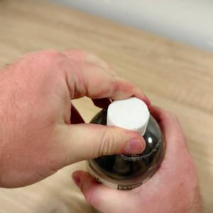 Eine Hand hält die Flasche während die andere Hand am Drehverschluss liegt.