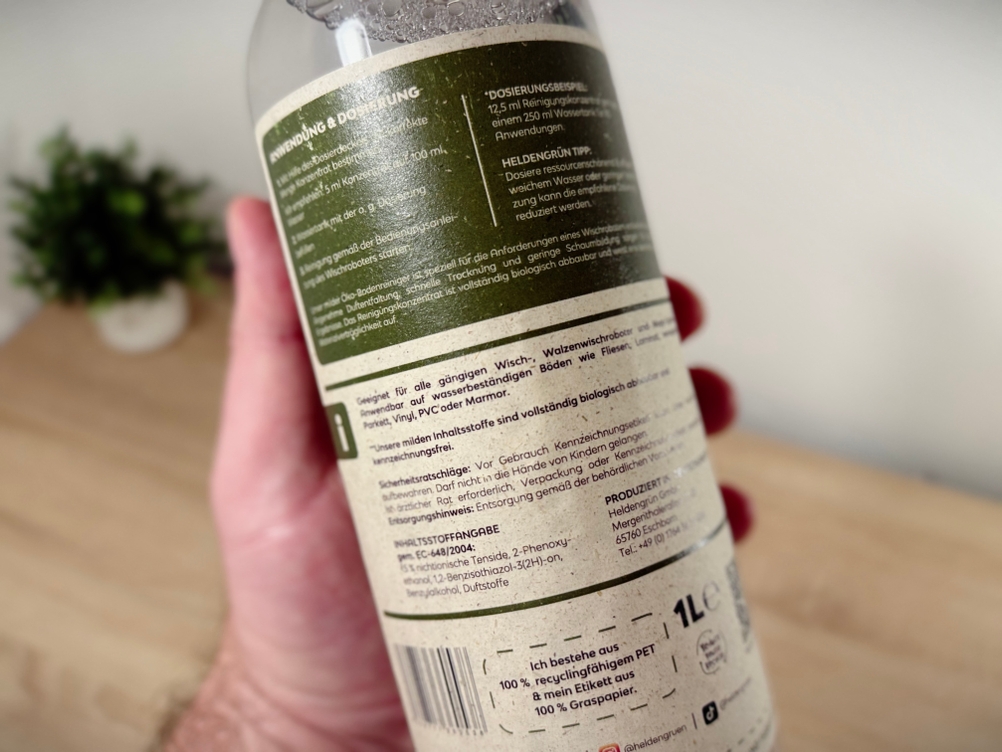 Eine Hand hält den Bodenreiniger Heldengrün.