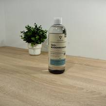 Der Bodenreiniger von Heldengrün steht auf einer hölzernen Platte vor einem weißen Hintergrund und einer Topfpflanze.