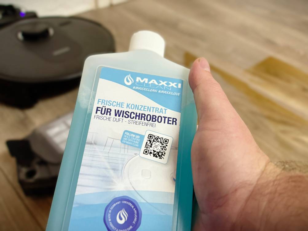 Eine Hand hält den Bodenreiniger von Maxxiclean.