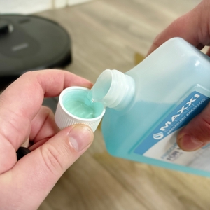 Es wird Bodenreiniger in den Deckel der Flasche gekippt.