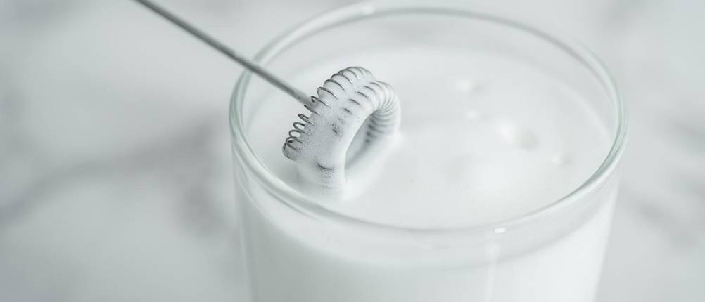 bodum-milchaufschäumer-test: Ansicht eines Stab-Milchaufschäumers in einer Tasse Milch 