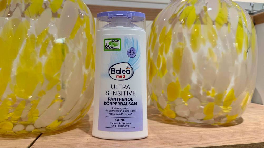 Zwischen zwei Vasen steht eine Flasche der getesteten Bodylotion ohne Parfüm.