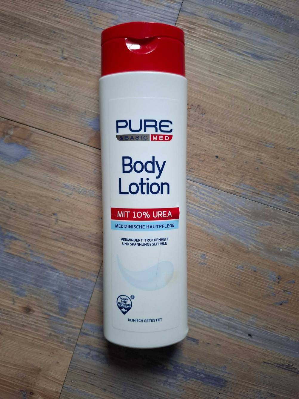 Eine getestete Bodylotion ohne Parfüm auf einem Holzboden liegend.