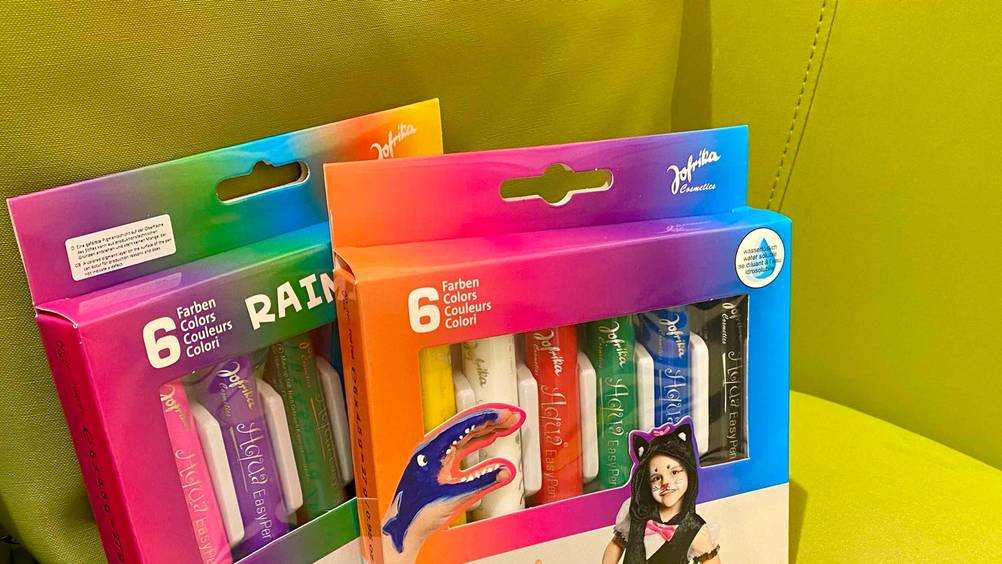 Nahaufnahme der Informationen auf der Originalverpackung von zwei Packung der getesteten Bodypainting-Farbe.