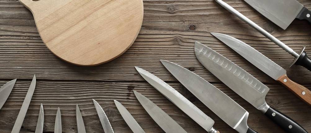 Boeker-Kochmesser-Test: Eine Sammlung von Messern auf schwarzem Holzuntergrund und neben einem Holzbrett.