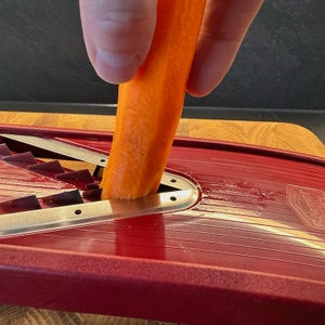 Karotte in der Hand, wird mit dem Börner-V1-ClassicLine-6-tlg.-Set geschnitten