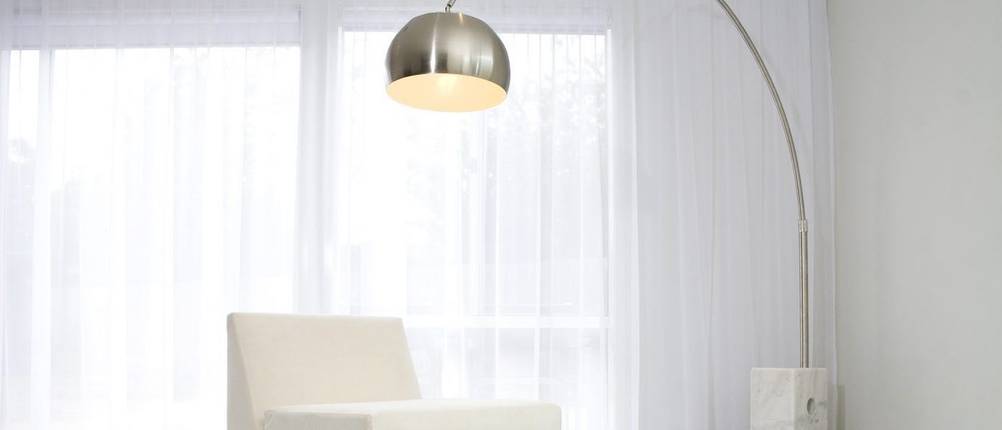 Bogenlampe-Test: Eine Bogenlampe mit Marmorfuß steht in einem hellen Wohnbereich.