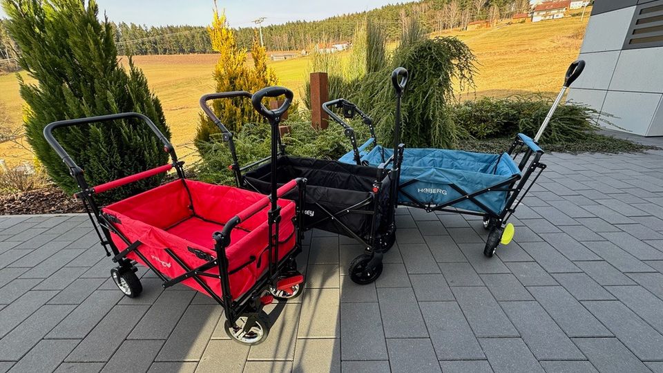 Alle drei Bollerwagen stehen nebeneinander auf einem gepflastertem Weg