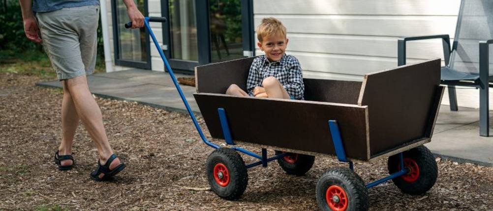 Bollerwagen-Holz-Test: Ein Junge sitzt in einem Holz-Bollerwagen. 