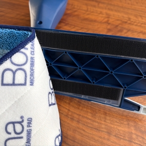 Ein Stoff wird von der Bodenplatte vom Bona-Bodenwischer entfernt.