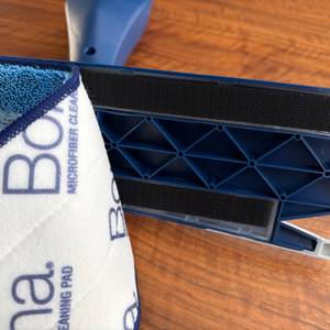 Ein Stoff wird von der Bodenplatte vom Bona-Bodenwischer entfernt.