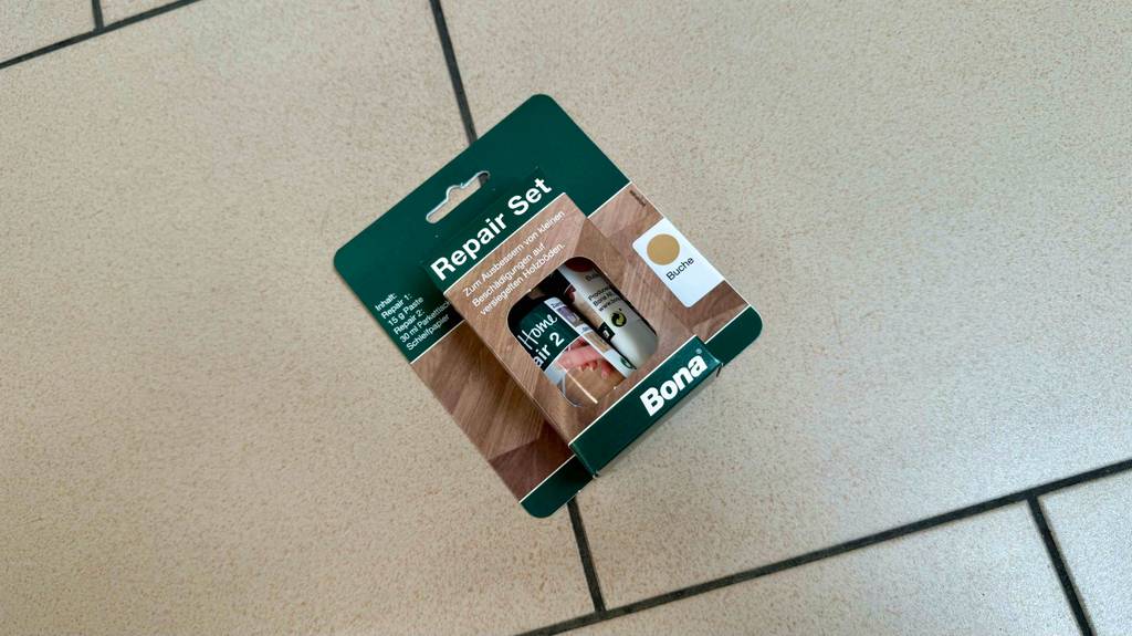 Parkett-Reparaturset-Test: Ein Set liegt in seiner Originalverpackung auf einem weißen Fliesenboden.