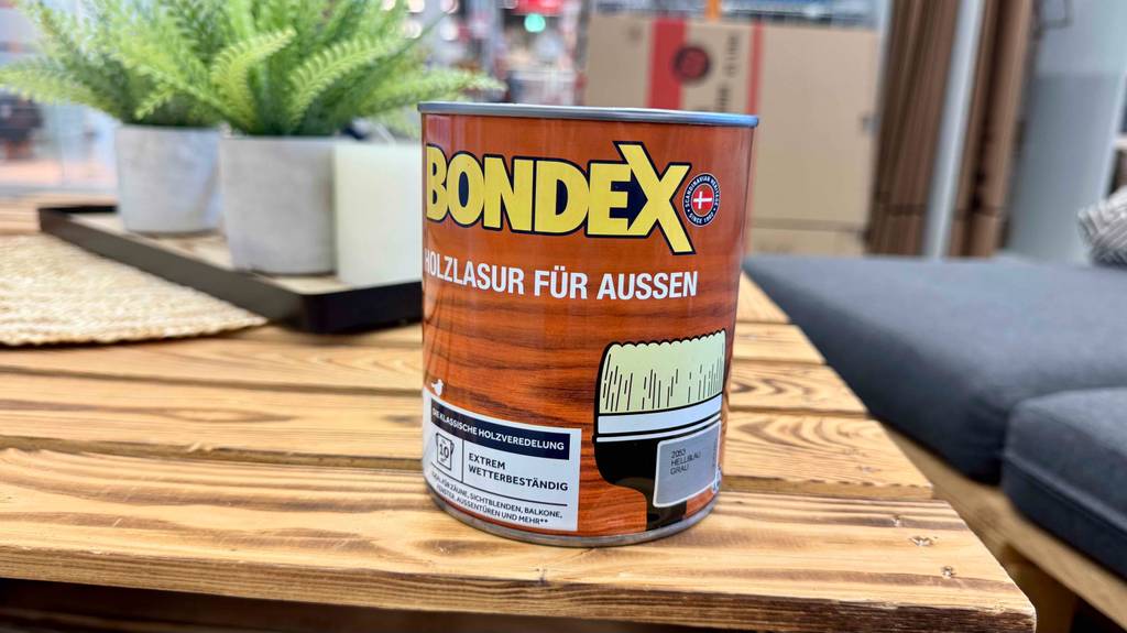 Eine Dose Holzlasur grau steht zum testen auf einem Holztisch.