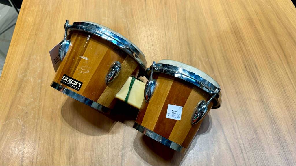Getestete Bongos auf der Seite liegend mit Preisangaben und Logo auf einer Holzfläche.