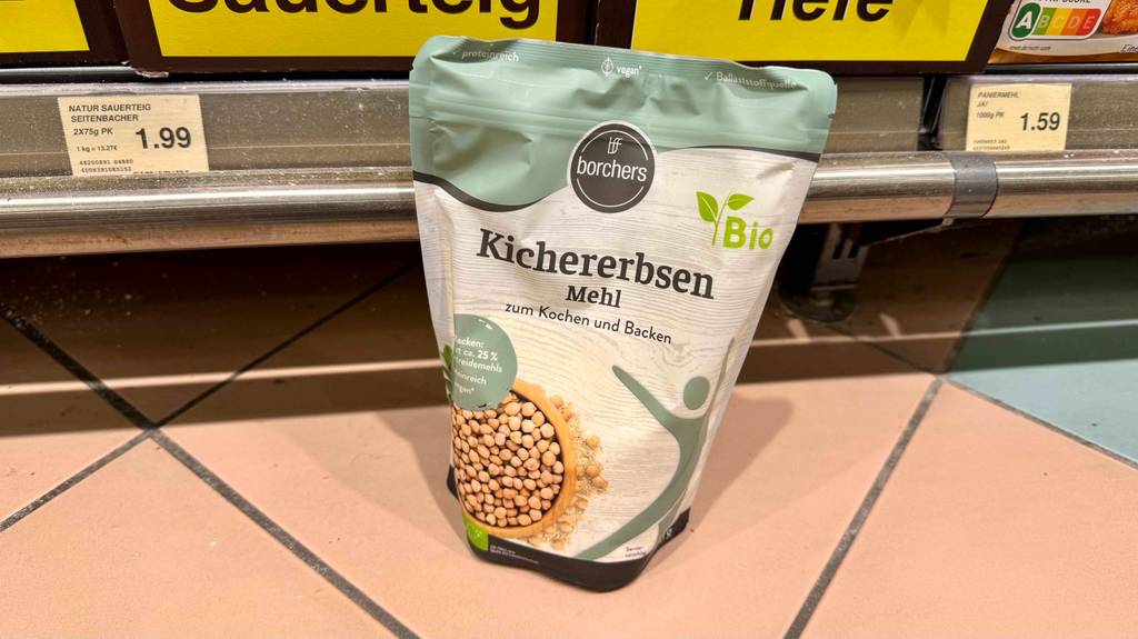 Ein wiederverschließbarer Beutel mit Borchers Kichererbsenmehl im Test steht vor einem Regal mit Lebensmitteln.
