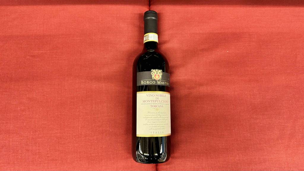 Eine Flasche Montepulciano-Wein liegt zum testen auf einer roten Fläche.