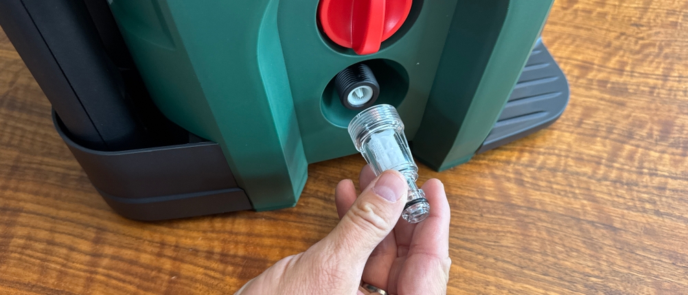 Eine Hand entfernt den Schlauchanschluss des Bosch AdvancedAquatak 140